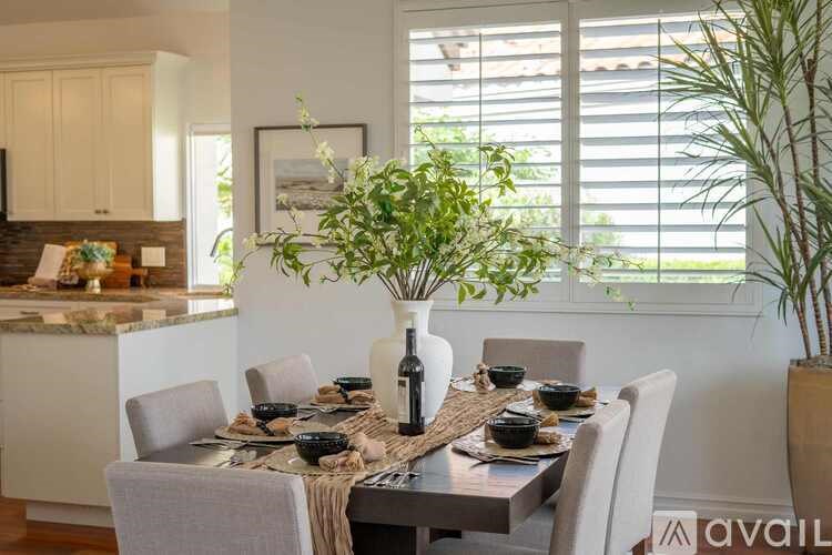 A dining table set with a vase of flowers in the middle.