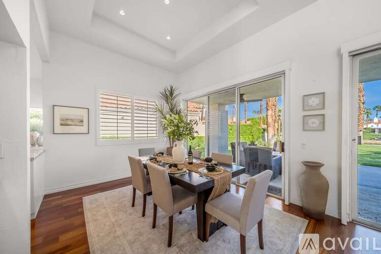 A dining room with a table set for four and a view of the backyard.