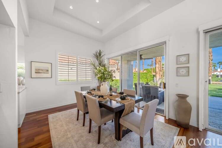 A dining room with a table set for four and a view of the backyard.