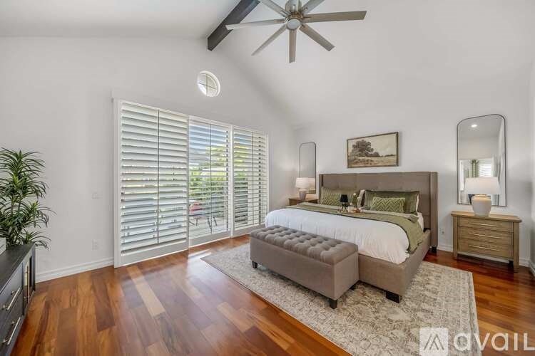 A bedroom with a bed, dresser, mirror, and a plant.