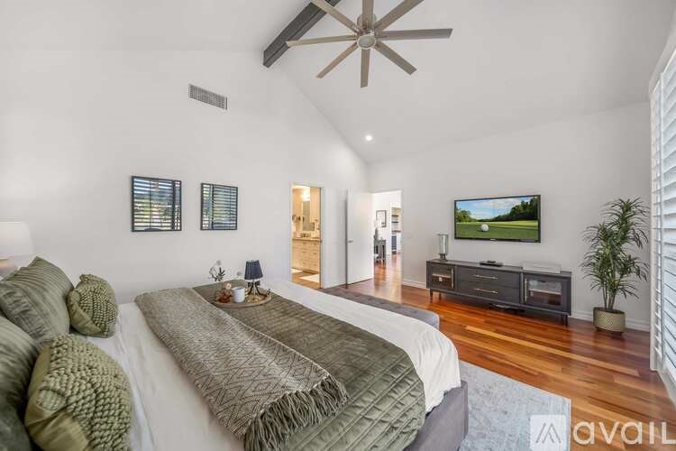 A bedroom with a large bed and a ceiling fan.