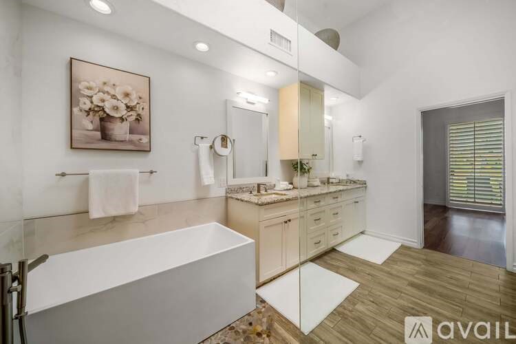 A bathroom with a tub, sink, and mirror.