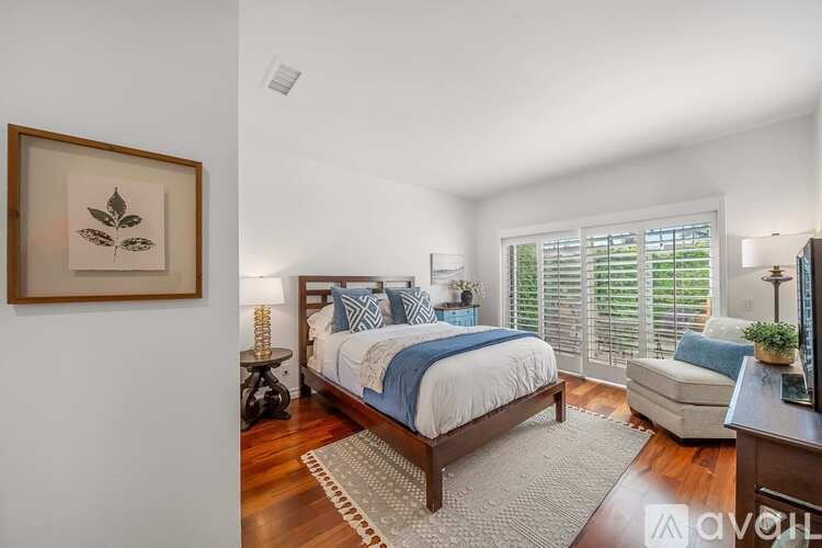 A bedroom with a bed, a couch, and a painting on the wall.