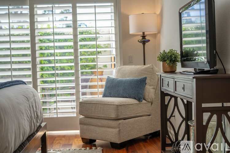 A bedroom with a bed, chair, and television.
