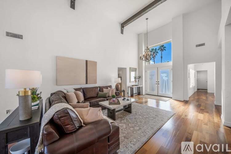 A living room with a brown leather couch and a grey rug.