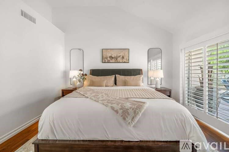 A bedroom with a large bed and a painting on the wall.