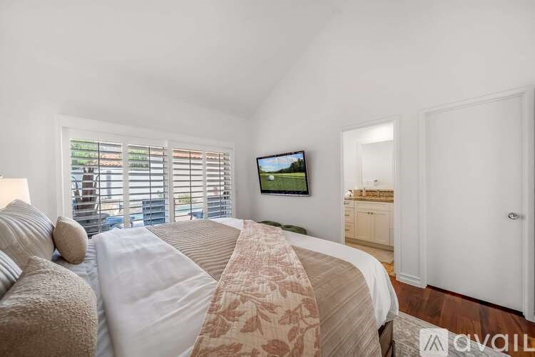 A bedroom with a large bed and a flat screen TV mounted on the wall.