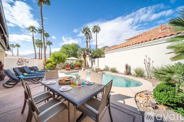 A patio with a table and chairs overlooking a pool.