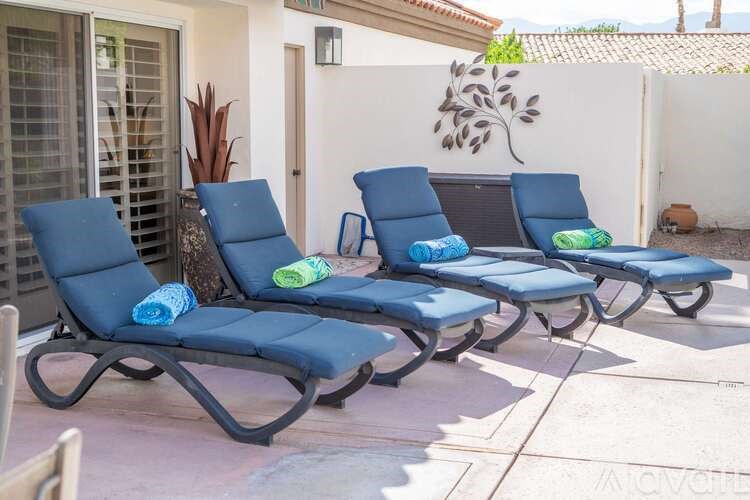 Three blue lounge chairs are arranged on a patio.