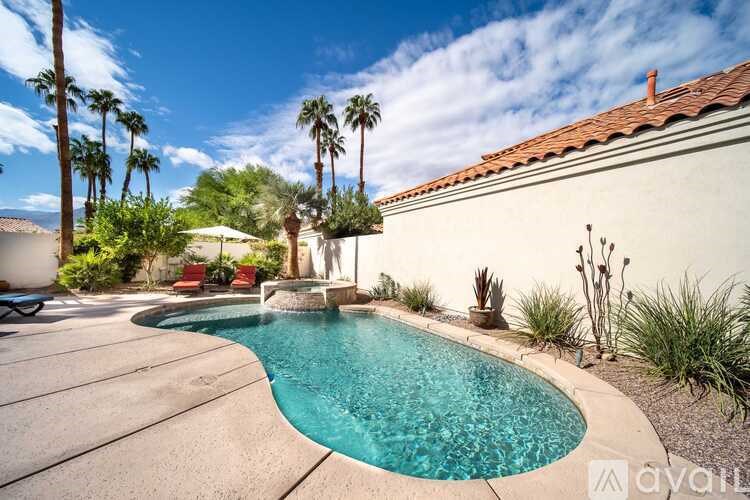 A pool surrounded by a patio and palm trees.
