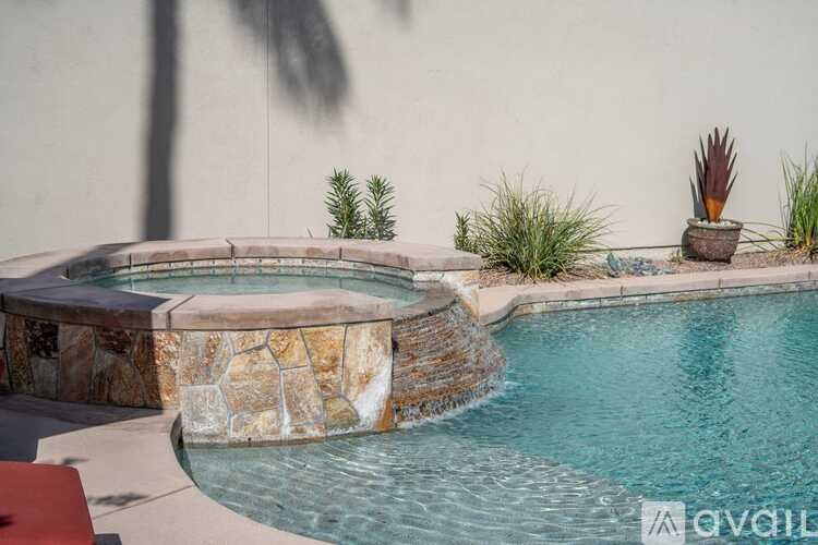 A pool with a waterfall and a stone wall.