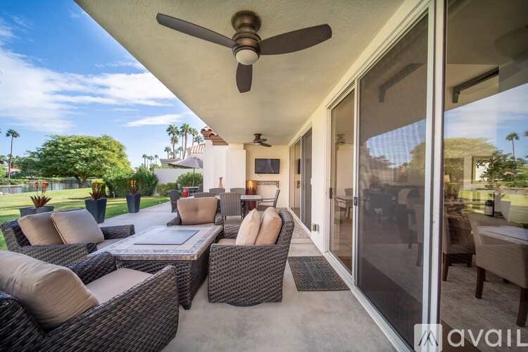 A patio with a ceiling fan and wicker furniture.
