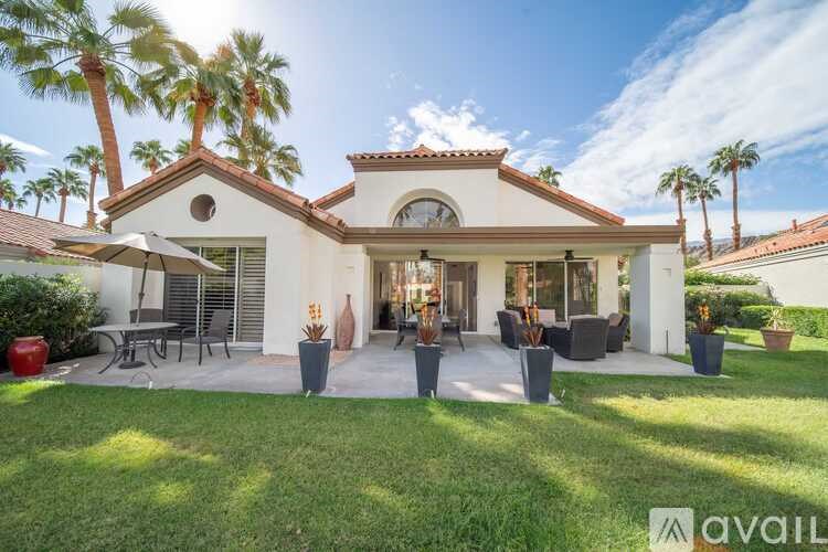 A house with a patio and palm trees in the background.