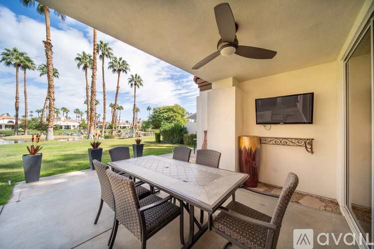 A patio with a table, chairs, and a ceiling fan.