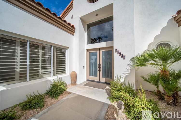 A white house with a brown roof and a glass door.