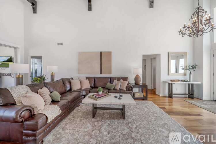 A living room with a brown leather couch and a coffee table in the center.