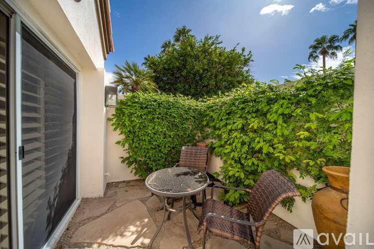 A patio with a table and chairs surrounded by greenery.