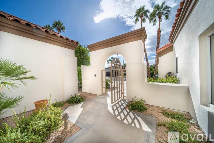 A sunny day at a house with a white wall and a brown roof.