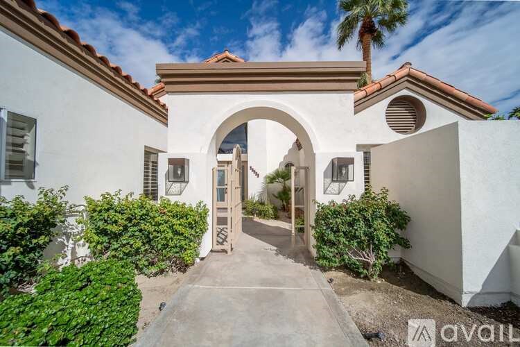 A white house with a red tile roof and a palm tree in the background.