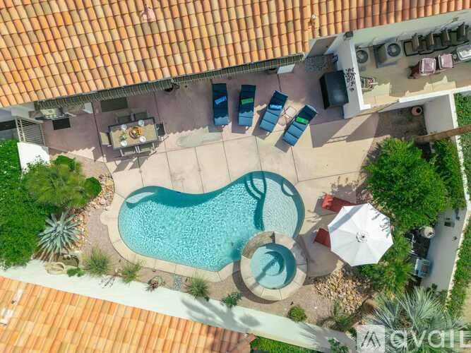 An aerial view of a pool surrounded by a deck and patio furniture.