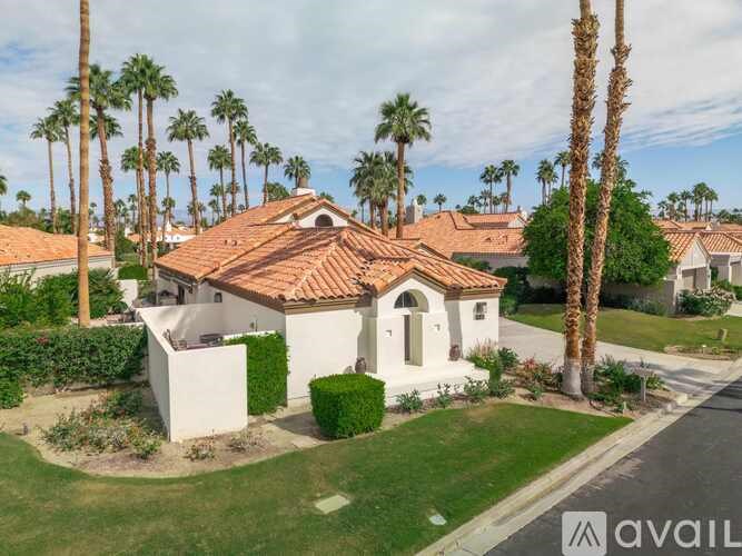 A house with a red tile roof is surrounded by palm trees.