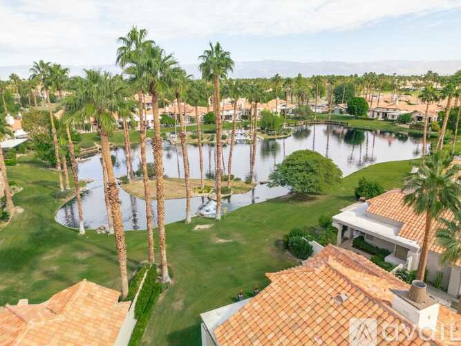 A beautiful view of a resort with a lake, palm trees and houses.