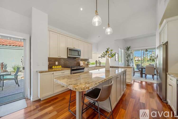 A kitchen with a marble island and a TV above it.
