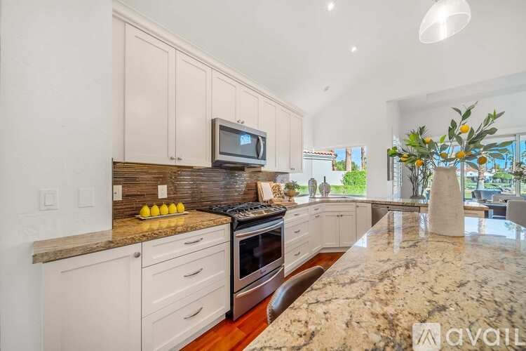 A kitchen with granite countertops and a TV on the counter.