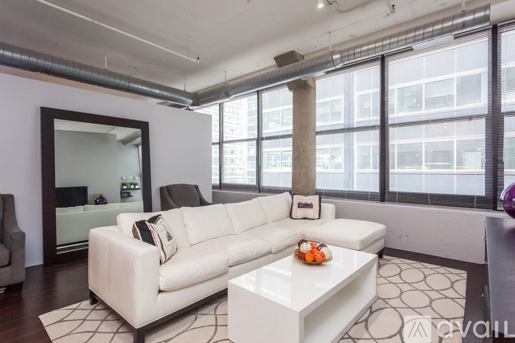 A white leather couch with a coffee table in front of it in a room with a large window.