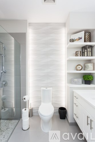A white toilet in a modern bathroom with a glass shower area.