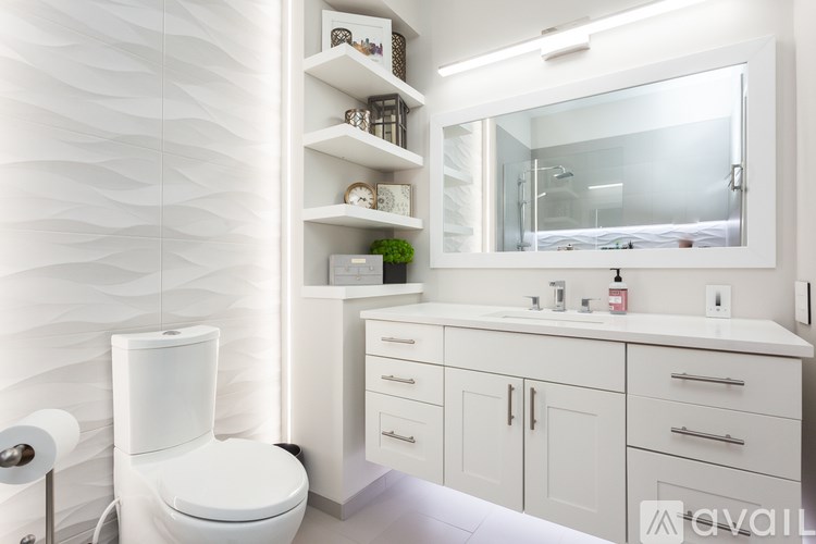 A white bathroom with a toilet, sink, and mirror.