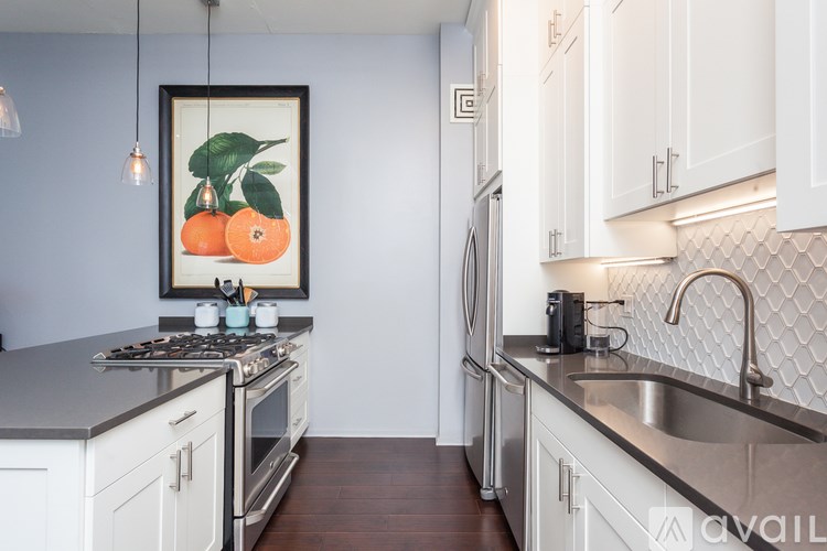 A kitchen with a framed picture of oranges on the wall.