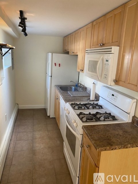 A kitchen with a white fridge, white stove, and wooden cabinets.