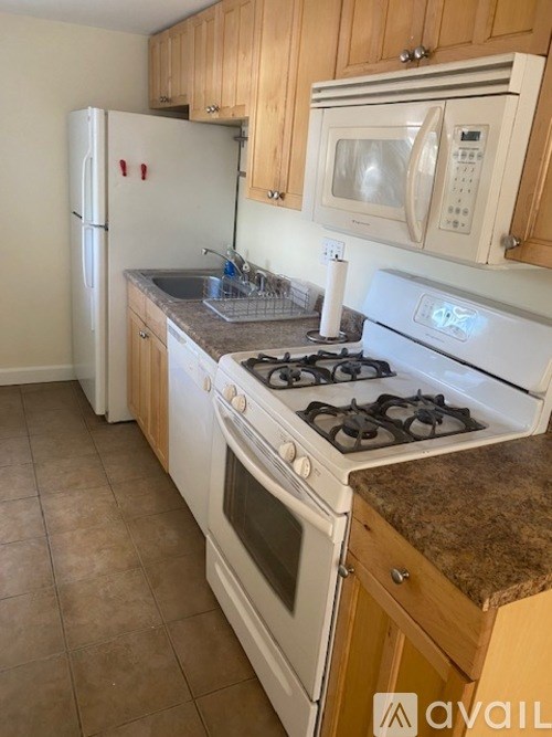 A kitchen with a white stove, refrigerator, and microwave.