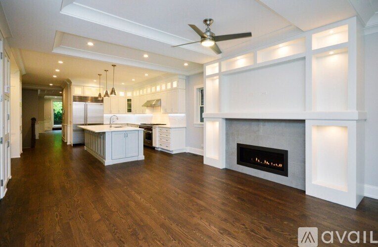 A spacious kitchen and living room with a fireplace and wood flooring.