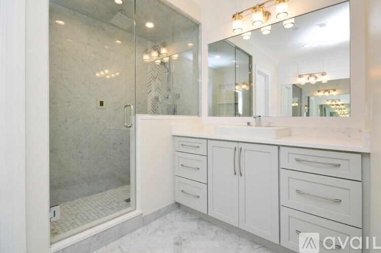 A bathroom with a walk-in shower, a sink, and a mirror.