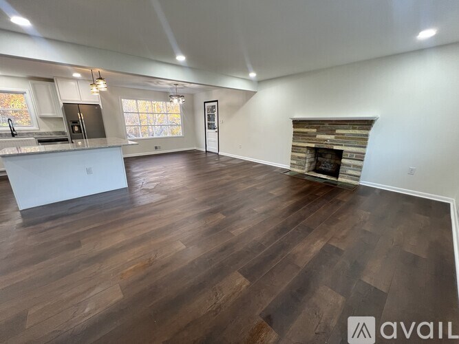 A spacious room with wooden flooring and a fireplace.