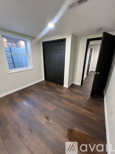 A room with a black door and wooden flooring.