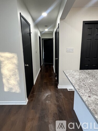 A hallway with dark wood floors and white walls.