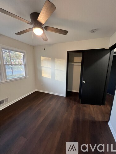 A room with a ceiling fan and wooden flooring.