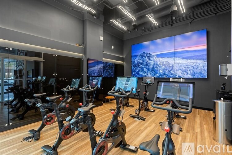 A gym with exercise bikes and a large screen on the wall.