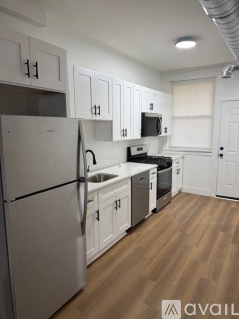 A kitchen with white cabinets and a stainless steel refrigerator.