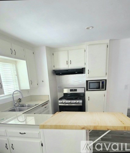 A kitchen with white cabinets and a wooden table.