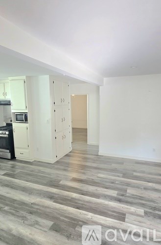 A kitchen with white cabinets and a wooden floor.