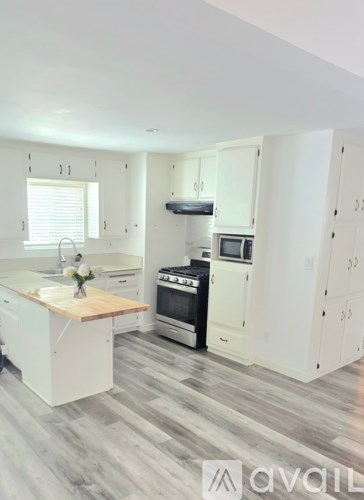 A kitchen with white cabinets and a wooden island.