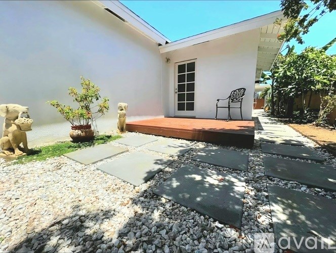 A white house with a wooden deck and a statue of a dog.