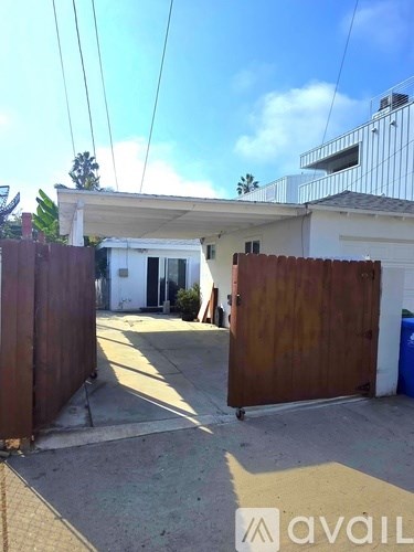 A wooden gate is closed in front of a white building.
