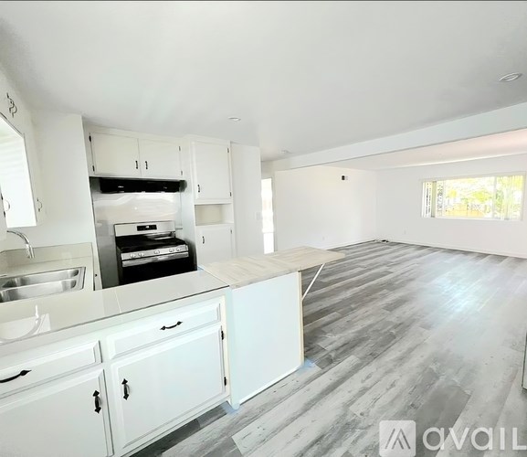 A kitchen with white cabinets and a wooden floor.