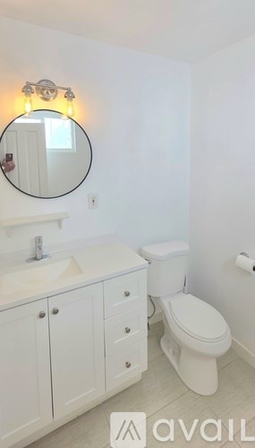A bathroom with a toilet, sink, and mirror.