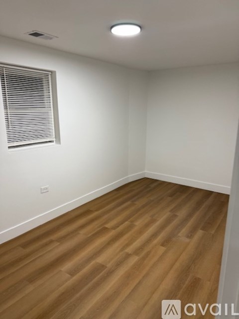 A room with wooden flooring and a window with blinds.